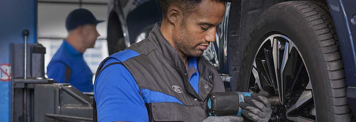 Ein Mechaniker wechselt einen Reifen mit einem Elektrowerkzeug in einer Werkstatt.