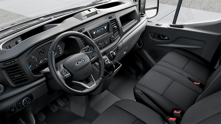 Innenansicht eines Ford Transporters, mit Lenkrad, Armaturenbrett und schwarzen Sitzen.